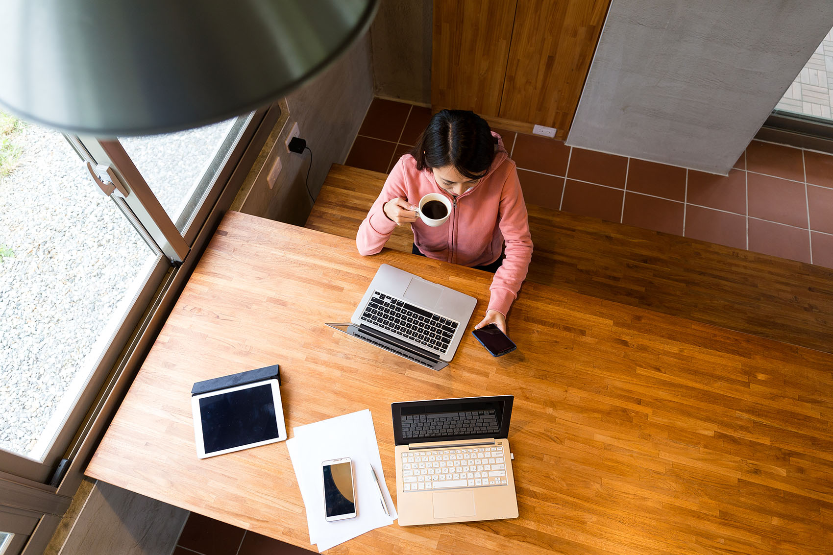 Aerial view of someone at a desk with coffee, using a phone at a workstation