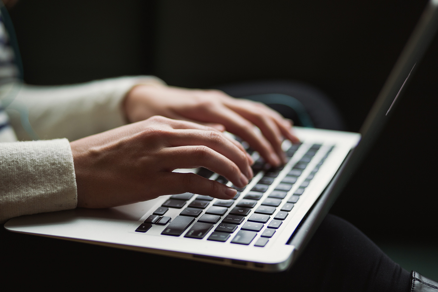 Hands typing on a MacBook keyboard
